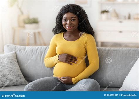 Beautiful Black Pregnant Woman Sitting On Couch At Home Stock Image