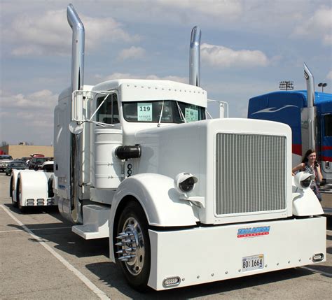 A Large White Semi Truck Parked In A Parking Lot Next To Other Trucks