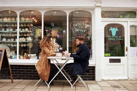 Couple Sitting Outside Cafe Enjoying Coffee And Snack Stock Photo