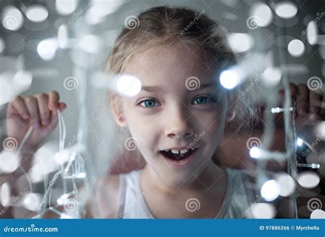 Retrato De Uma Menina Pré Escolar Bonito Com Uma Festão Brilhante Das Luzes Em Suas Mãos Foto De