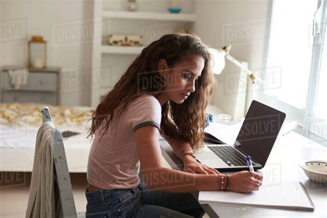 Teenage Girl Doing Homework At A Desk In Her Bedroom Stock Photo
