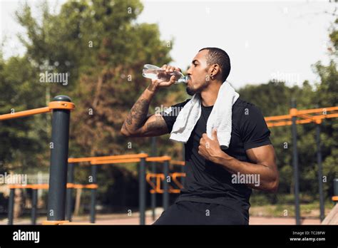 Sporty Man Drinking Water After Workout At Sports Ground Stock Photo