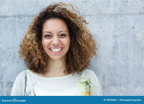Portrait Of A Beautiful Young Woman With Curly Hair Smiling Outdoors