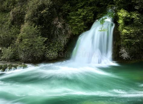 Long Exposure Shot Of Small Foaming Waterfall With Turquoise Colored