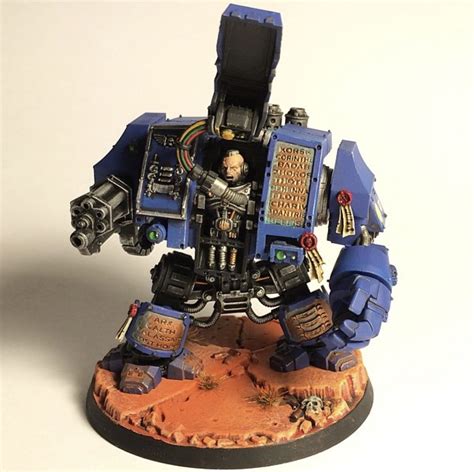 A Blue And Black Warhammer Is Standing On A White Surface With His Arms