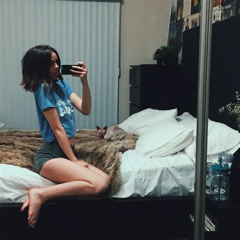 A Woman Taking A Selfie While Sitting On A Bed In Front Of A Mirror
