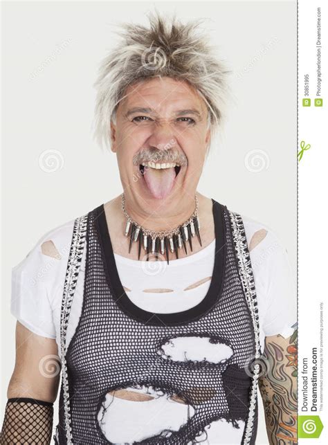 Portrait Of Senior Male Punk Sticking Out Tongue Over Gray