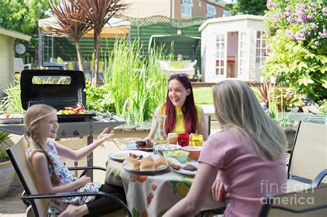 Lesbian Couple And Daughter Enjoying Barbecue Photograph By Caia Image