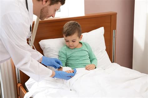 Doctor Adjusting Intravenous Drip For Little Child In Hospital During