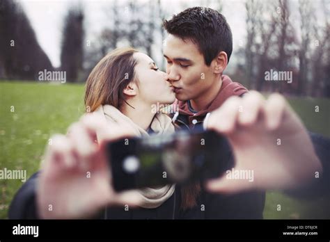 Lovely Young Couple Taking Self Portrait While Kissing At The Park