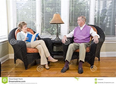 Senior Couple Sitting On Living Room Chair Reading Royalty Free Stock