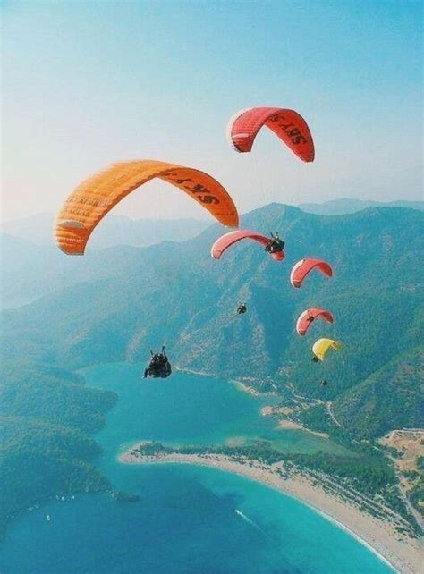 Several Parasailers Are Flying Over The Ocean And Mountains