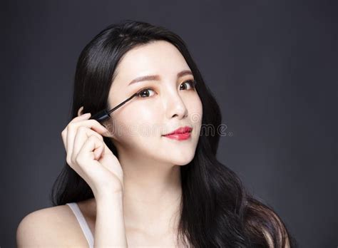 Young Woman Applying Black Eye Mascara To Her Eyelashes Stock Image