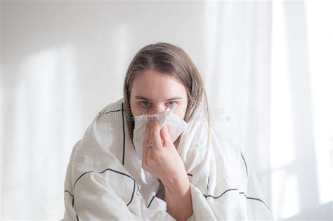 Ill Woman Under White Blanket Blowing Her Nose On White Background