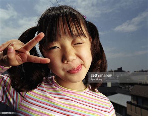 Girl Sticking Out Tongue Making Peace Sign With Hand Portrait High Res