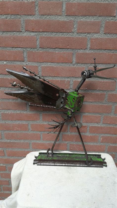 A Metal Insect Sculpture Sitting On Top Of A White Table Next To A