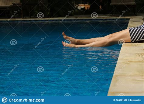 Beautiful Slim Naked Women Legs Hanging Out In The Clear Blue Water Of The Pool In Sunny Day