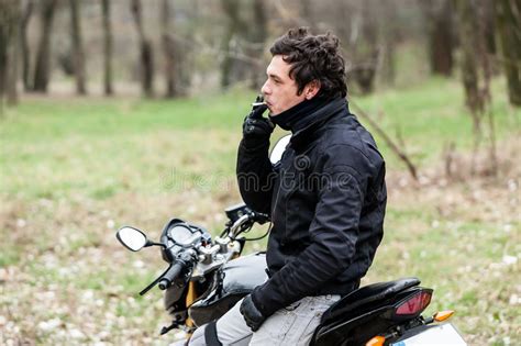 Biker Sitting On Motorcycle And Smoking His Cigarettes Stock Image
