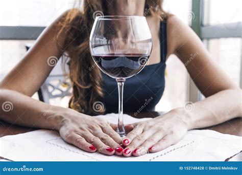 Drunk Woman Sitting At A Table And Holding A Glass Of Wine Close Up