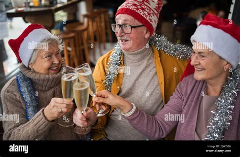 Happy Senior Friends Indoors In Cafe Clinking Champagne Glasses And Celebrating Christmas Stock