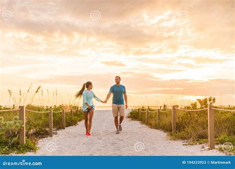 Happy Young Couple In Love Walking On Romantic Beach Stroll At Sunset