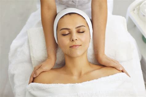 Cosmetologist Making Massage Of Face Neck And Upper Shoulder Girdle For Relaxed Young Woman In