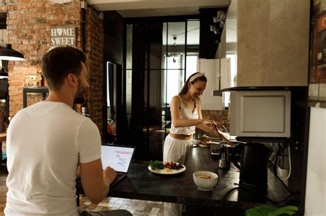 Die Frau Kocht In Der Küche Der Mann Arbeitet Ehepaar Spricht In Der Küche Premium Foto