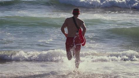 Male Lifeguard Running Along The Beach Stock Footage Videohive
