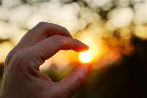 Premium Photo Optical Illusion Of Hand Holding Sun During Sunset