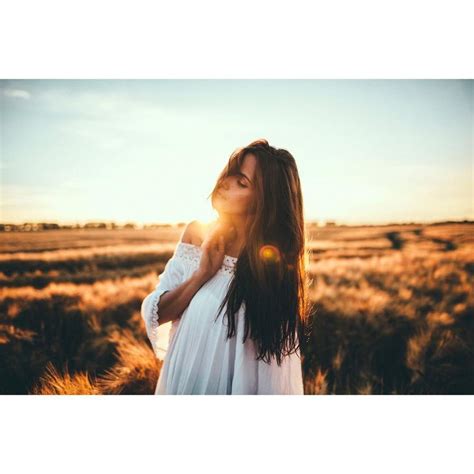 A Woman In A White Dress Is Standing In A Field With The Sun Shining Through Her Hair
