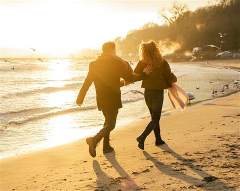 paar das im winter zusammen am strand spazieren geht kostenlose foto