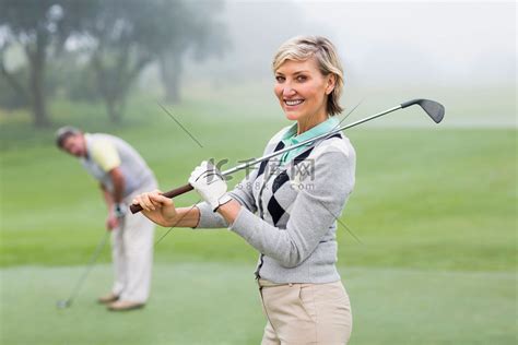 女高尔夫球手对着镜头微笑，背后有搭档高清摄影大图 千库网