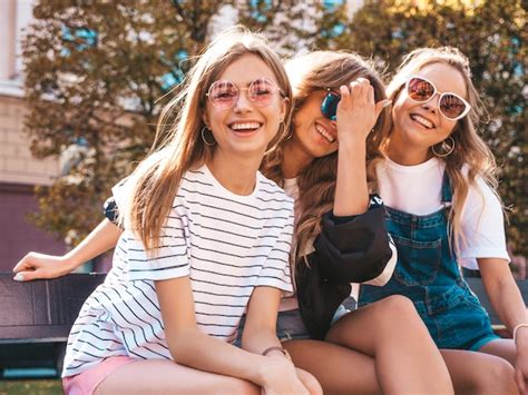 トレンディな夏服の3人の若い美しい笑顔流行に敏感な女の子の肖像画。路上でポーズをとってセクシーな屈託のない女性。サングラスで楽しんでいる