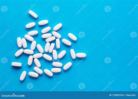 White Large Oval Pills are Scattered on a Blue Background. Medicines