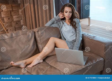 Young Woman Sitting On Sofa And Concentrate Using The Laptop Stock