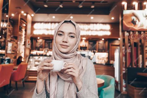 Premium Photo A Cute Muslim Woman With A Headscarf On Her Head Drinks
