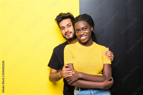 Young Happy Mixed Race Couple Indian Man And African Woman Hug Isolated On Yellow Black