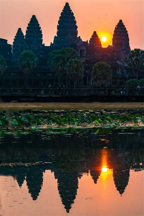 The Sun Is Setting In Front Of An Ancient Temple With Water Lillies And