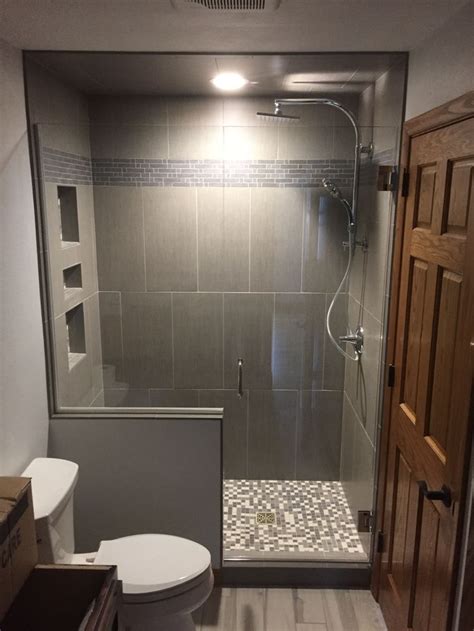 a bathroom with a walk in shower next to a white toilet and wooden door on the wall