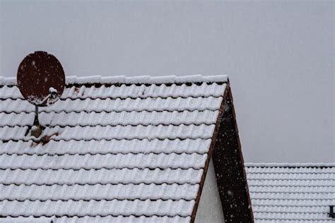 Tiled Roof Of A House With A Satellite Dish Covered With Snow Stock