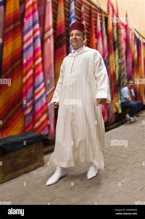 Man In Traditional Moroccan Clothing Walking Past Colourful Fabrics For