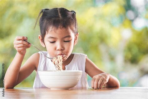 Cute Asian Child Girl Eating Delicious Instant Noodles With Fork In The