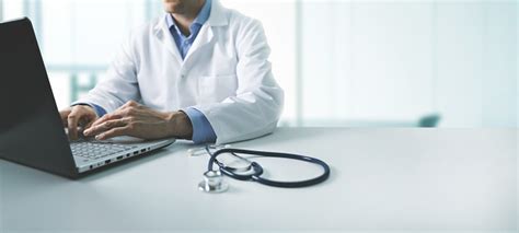 Online Medical Consultation Doctor Working On Laptop Computer In Clinic