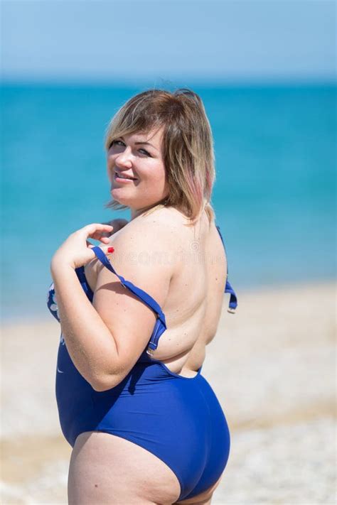 Overweight Woman In Blue Bikini Standing Arms Akimbo Outdoors Stock