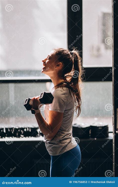 Slender Athletic Girl Performs Physical Exercises With Dumbbells Stock