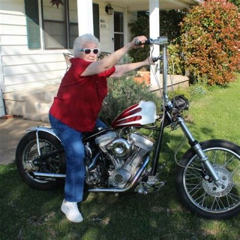 An Older Woman Sitting On Top Of A Motorcycle In Front Of A House With