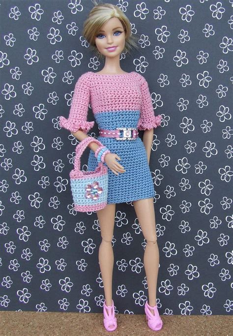 a barbie doll is holding a purse and posing for the camera in front of a wall