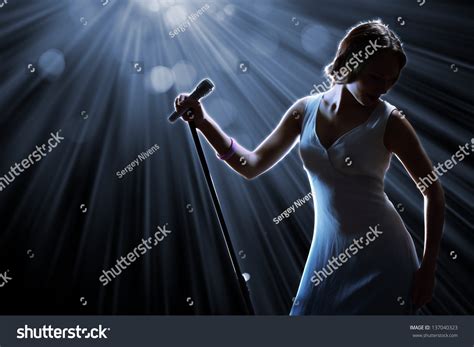 Female Singer On Stage Holding Microphone Stock Photo