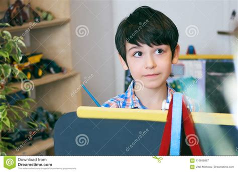 Child Standingnext To The Easel Kid Boy Learn Paint By Brush In Class