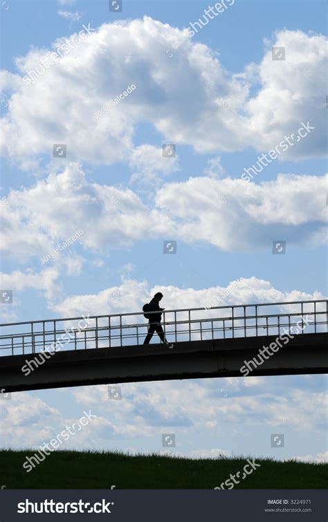 Young Man Crossing Bridge Against Bright Blue Sky Stock Photo 3224971